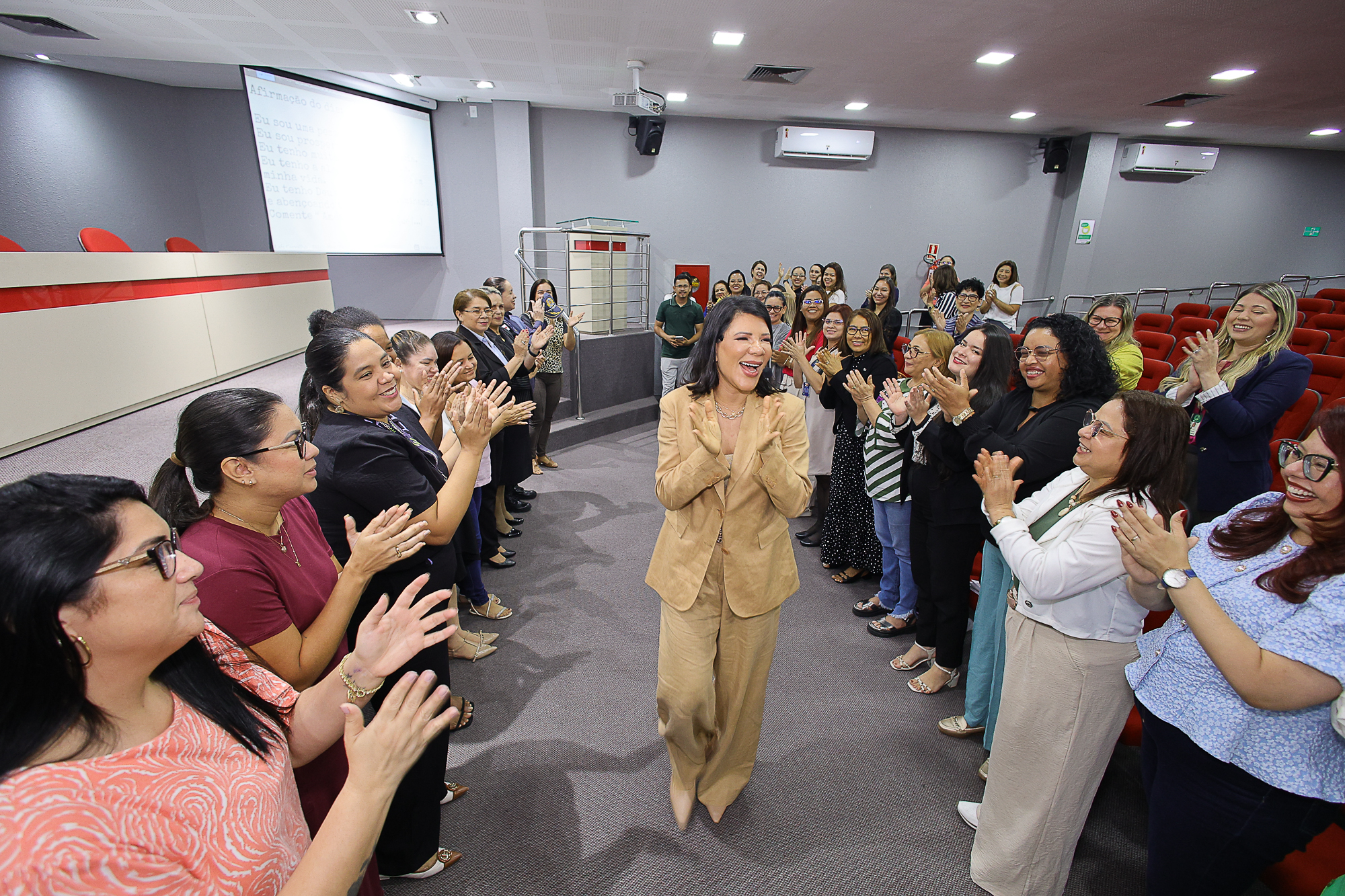 Mulher aplaudida pelo público durante uma palestra